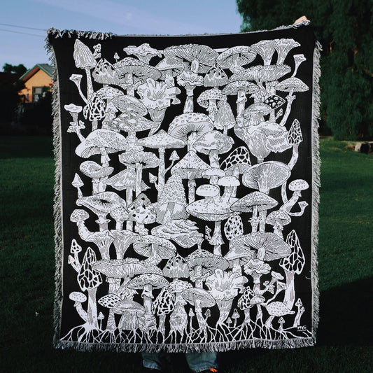 Black blanket with white mushroom pattern held by a person outdoors